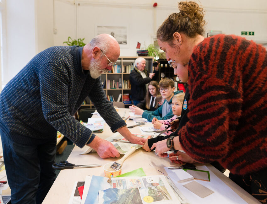 An adult and a child in a bookmaking workshop with the artist demonstrating.