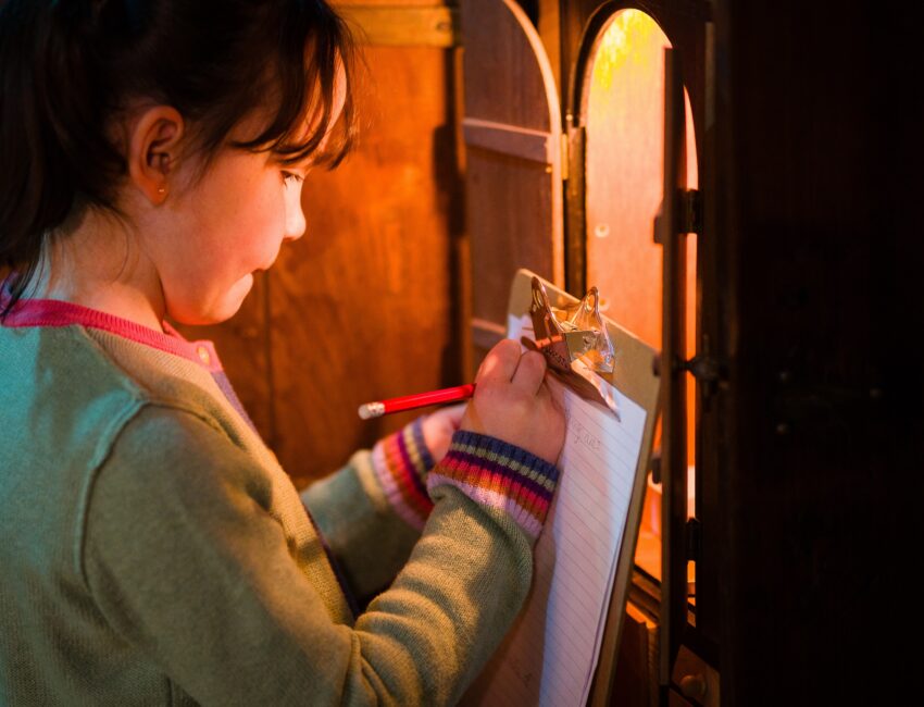 Girl writing on clipboard looking into lit cupboard. Inage by Steve Tanner