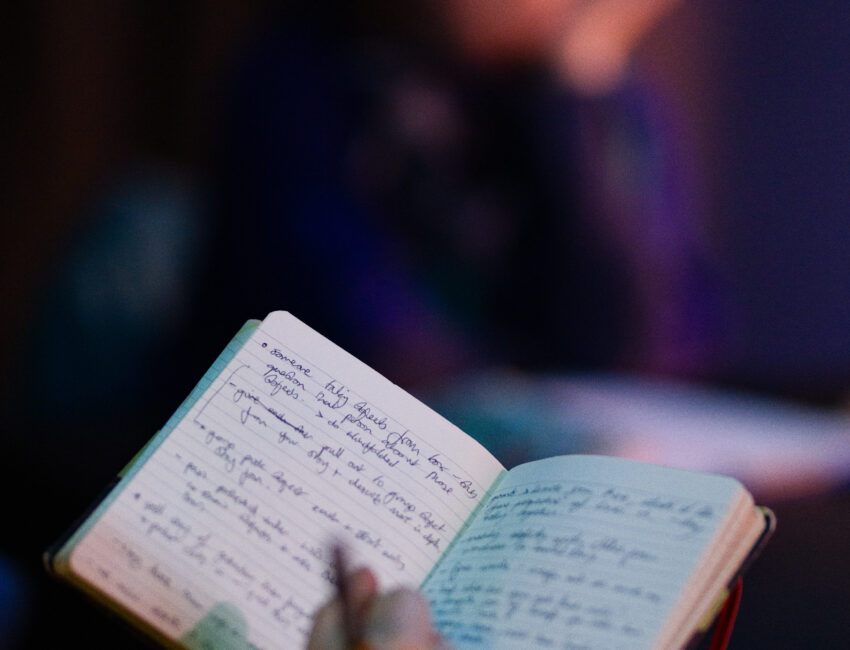 Photograph of a hand writing in a full notebook