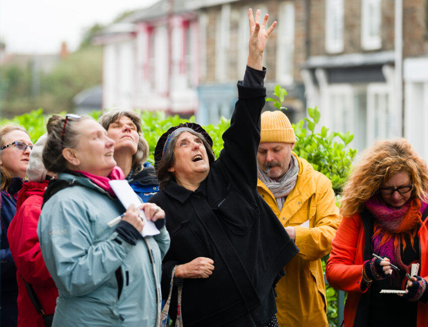 A group of writers in the street point up towards the sky