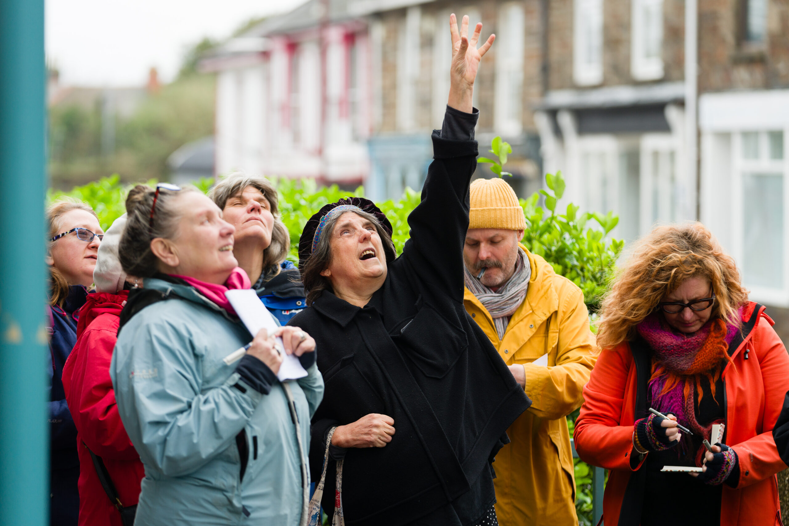 A group of writers in the street point up towards the sky